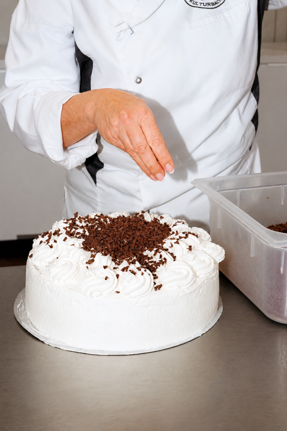 Ein Kuchen wird von Hand mit Schokolade verziert